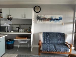 a kitchen with a chair and a clock on the wall at Beach House On 18p Repens in Mossel Bay