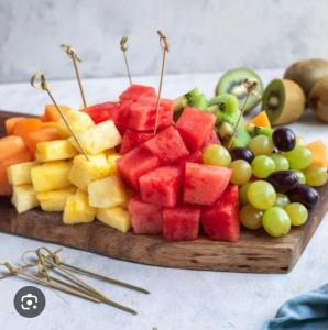 una tabla de cortar llena de fruta en una mesa en N M Hotel Nr kokilaben Hospital, en Bombay