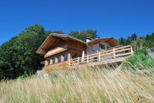 Guest House Dolomiti في باسيلغا دي بيني: منزل خشبي في حقل من العشب الطويل