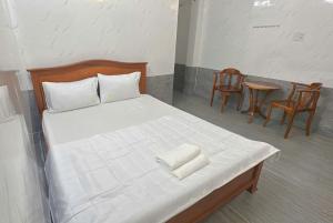 a bedroom with a bed with white sheets and chairs at Nhà Nghỉ Quỳnh Thoa in My Tho +3 photos