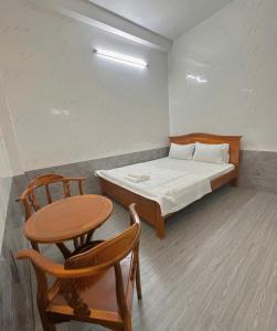 ein Zimmer mit einem Bett, einem Tisch und Stühlen in der Unterkunft Nhà Nghỉ Quỳnh Thoa in Mỹ Tho + 1 Foto