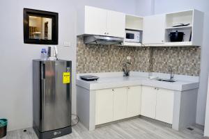 a kitchen with a refrigerator and white cabinets at Dachannry's Place Hotel in Cagayan de Oro