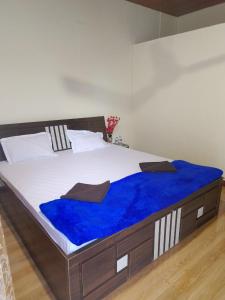Una cama grande con una manta azul encima. en fm cottage, en Murud