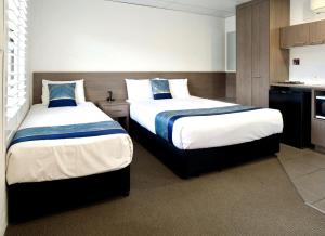 a hotel room with two beds and a kitchen at Chalet Motor Inn in Bundaberg +27 photos