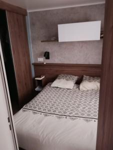a small bedroom with a bed with a white mattress at MH330 2 chambres et 1 salle de bain dans camping 4 étoiles in Saint-Julien-en-Born +8 photos