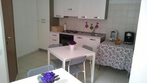a kitchen with a white table and chairs and a table with purple flowers at B&B I Tre Bassotti in Loreto