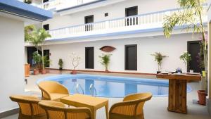une piscine avec des chaises et une table et un bâtiment dans l'établissement Mint By SR, à Calangute