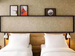 2 bedden in een hotelkamer met witte kussens bij ibis London Sutton Point in Sutton +94 foto's