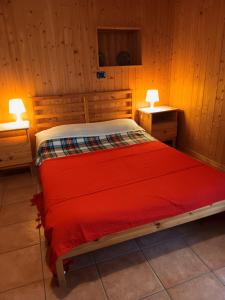 a bedroom with a red bed with two lights on two tables at La Casa Antica in Pont-Saint-Martin