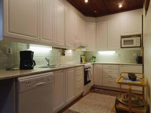 una cucina con mobili bianchi e un lavandino di Kuusirinne a Syöte