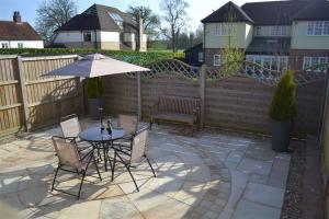 a patio with a table and chairs and an umbrella at The Cartlodge in Sudbury