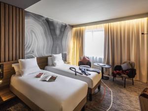 a hotel room with two beds and a chair at Novotel Cambridge North in Cambridge