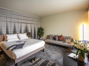 a bedroom with a large bed and a couch at Novotel Cambridge North in Cambridge +120 photos