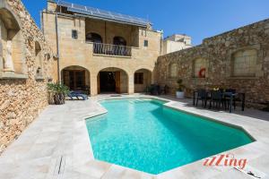 a swimming pool in the courtyard of a building at Gozo Farmhouse Escape with Rustic Charm & Pool in Sannat