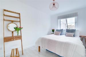 ein weißes Schlafzimmer mit einem Bett und einem Spiegel in der Unterkunft The Beach Snug in Woolacombe