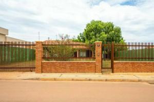 a red brick fence with a gate in front at Canto da Árvore in Brasilia