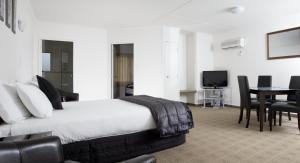 a bedroom with a bed and a table with chairs at Hygate Motor Lodge in Hamilton