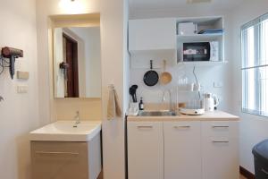 a small white kitchen with a sink and a mirror at Cozy Attic Retreat Chinatown near Yaowarat - Songwat in Bangkok