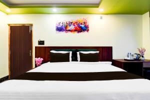 a bedroom with a large bed and a painting on the wall at Collection O AIIMS Kolkata Tanishq Inn in Kalyani