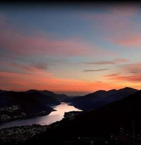 a view of a river at sunset with mountains at Lake Lugano Cademario LakeView Apartment BEST SUNSET & SUNRISE in Ticino in Cademario +10 photos