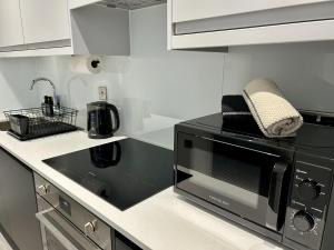 a kitchen with a black microwave and a sink at 5 Aviv Place in Addlestone