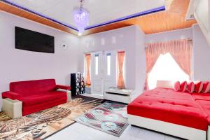 a living room with a red couch and a chair at OYO 94702 Putra Family Homestay Sikunir in Kejajar