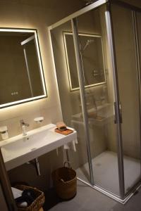 a bathroom with a glass shower and a sink at Boutique Hotel La Couronne Mies in Mies