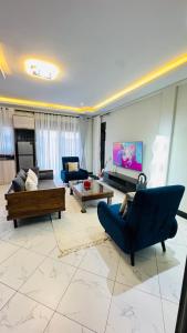 a living room with blue couches and a tv at Ikamba Homes-Munyonyo in Kampala