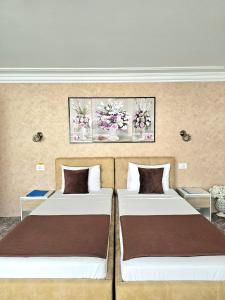 two beds in a room with two paintings on the wall at Pensiunea Ghiocela in Motru