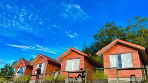 a man standing in front of two wooden homes at Pondok Alengkong in Bangli