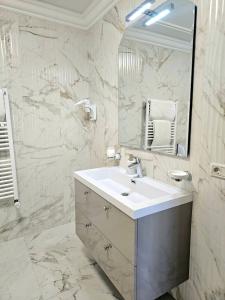 a white bathroom with a sink and a mirror at Pensiunea Ghiocela in Motru