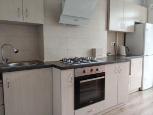 a kitchen with white cabinets and a stove and a sink at Апартаменти ЖК Скеля in Yaremche