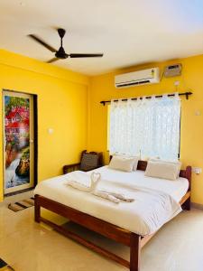 a bedroom with a large bed with yellow walls at Chelsea inn in Calangute +8 photos