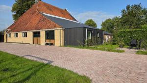 a building with a pitched roof and a brick driveway at MagnaFrisia in Gauw