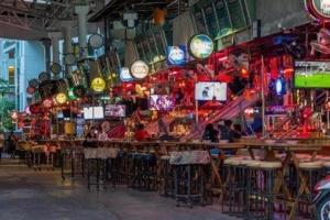 a restaurant with bar stools and clocks on the wall at The Nice Patong Hotel in Ban Nong Chaeng