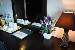 a desk with a lamp and a vase of flowers at The Nice Patong Hotel in Patong Beach