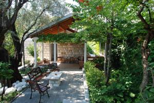 eine Terrasse mit Bänken und einem Tisch im Garten in der Unterkunft Holiday Home Olive Tree in Budva