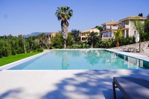 a large swimming pool with a palm tree and a building at The Seven Islands Deluxe Apartments in Gouvia