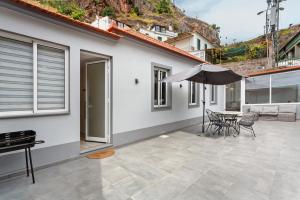 a patio with an umbrella and a table and chairs at Moradia Centro Da Cidade Funchal in Santa Luzia