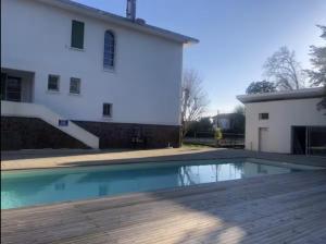 a swimming pool in front of a white building at Chambre 2 Bleue - WIFI - Proche gare in Labouheyre