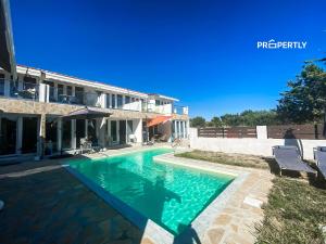 a swimming pool in front of a house at Oasis by the Pool in Nea Kallikrateia
