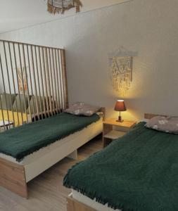 a bedroom with two beds with green sheets and a lamp at TESTkg in Cholpon-Ata