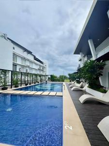 a hotel swimming pool with white lounge chairs next to a building at Davao Condo Bed Space - Safe, Affordable & Comfy in Davao City