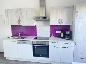 a kitchen with white cabinets and a sink at Apartment mit Balkon & Bergblick inklusive Parkplatz in Christofberg