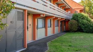 a row of buildings with orange trim and a garage at Campanile NATURE - Epône in Épône