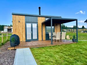 a house with a deck with chairs and a table at Czech Tinyhouse Lasówka in Lasowka