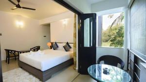 une chambre avec un lit, une table et une fenêtre dans l'établissement Mint By SR, à Calangute 10 autres photos
