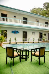 une table et deux chaises devant un bâtiment dans l'établissement Mint By SR, à Calangute