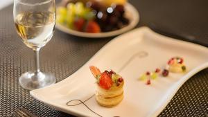 - une assiette blanche avec un dessert et un verre de vin dans l'établissement Mint By SR, à Calangute