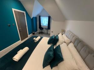 Luxury 4BR Home with Hot Tub, Sleep 8, Free Parking, Garden في Kenley: غرفة نوم بسرير كبير ومخدات خضراء وبيضاء